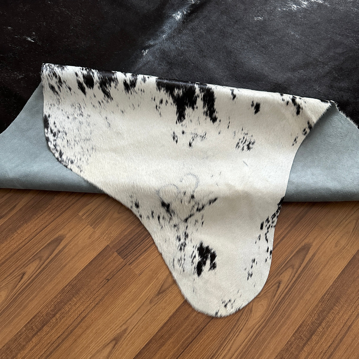 Close-up texture of Black and White cowhide rug — Large irregular dark patches over cream-white base with natural spotting