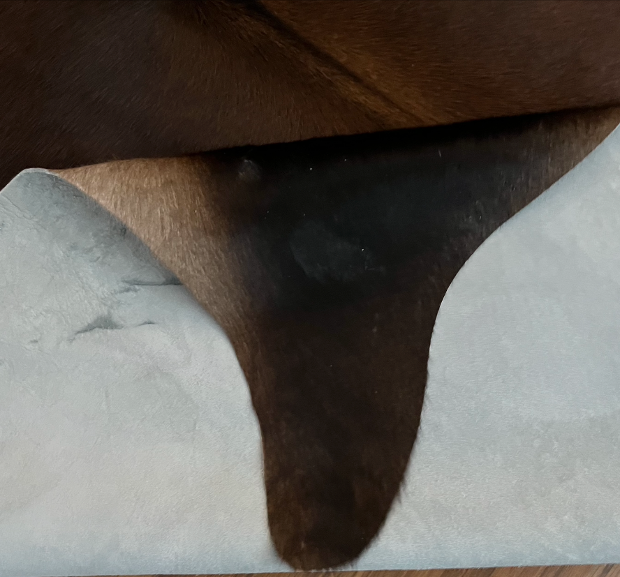 Close-up texture of Black and White cowhide rug — Large irregular dark brown-black patches with cream and white undertones