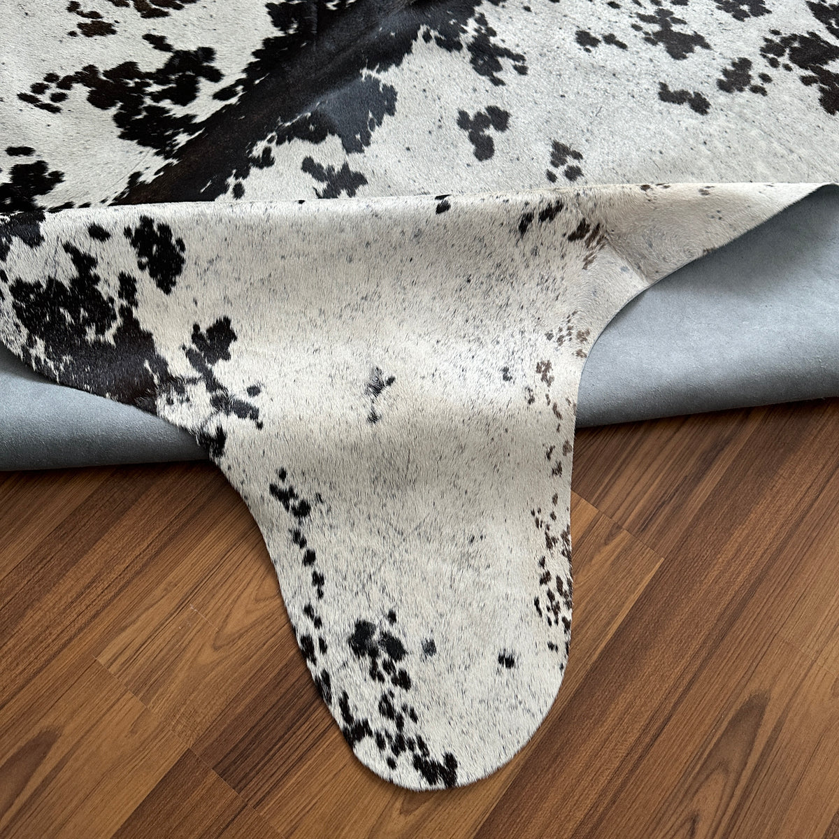 Close-up texture of Black and White cowhide rug — Large irregular dark brown patches with fine speckle over cream and white b