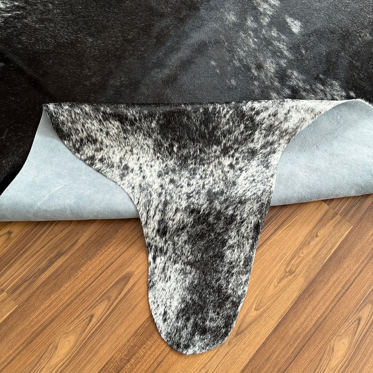 Close-up texture of Black and White cowhide rug — Large irregular black and white patches with salt-and-pepper speckle textur