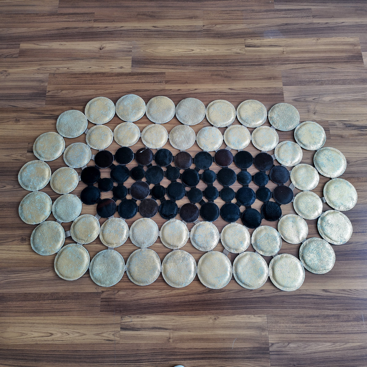 Black and White round patchwork cowhide rug, full overhead view — Alternating cream and black circular hide discs arranged in