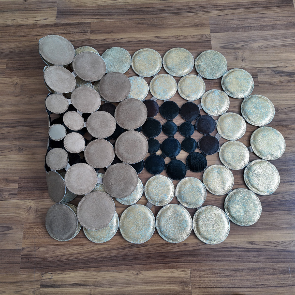 Close-up texture of Black and White round patchwork cowhide rug — Alternating cream and black circular hide discs arranged in