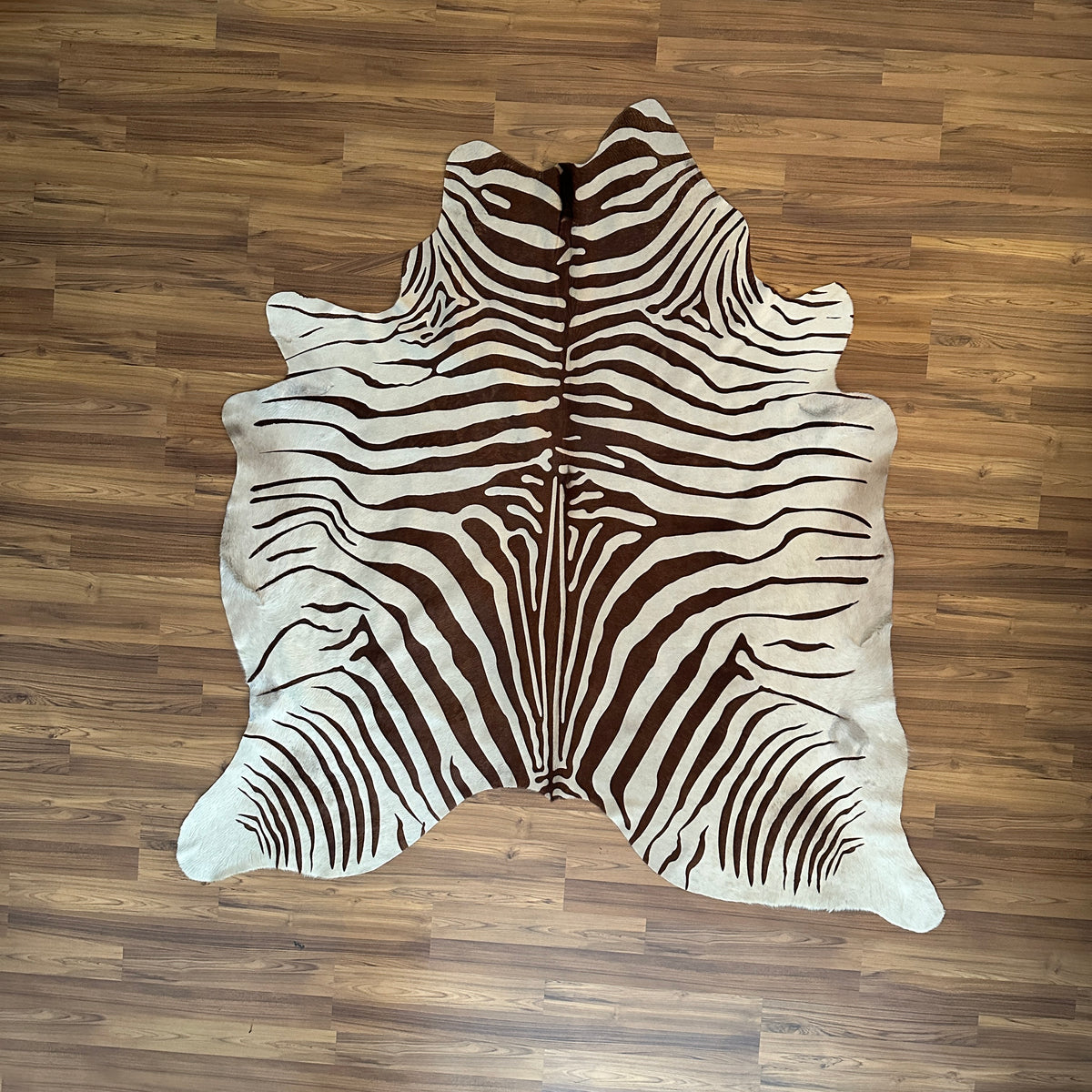 Brown and White zebra print cowhide rug, full overhead view — Bold zebra stripes radiating from center, dark brown on cream b