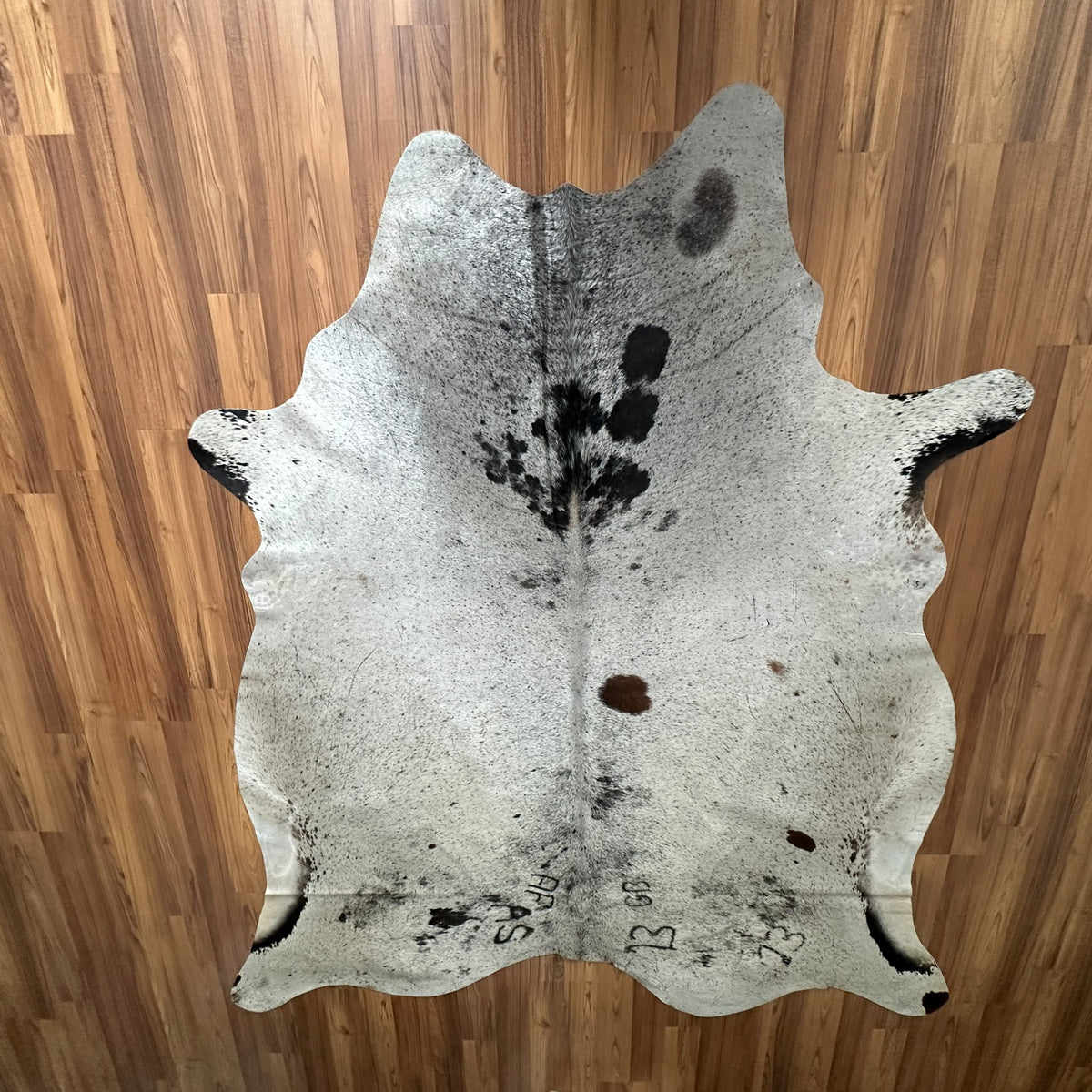 Brown and White cowhide rug, full overhead view — Large irregular dark brown patches and spots over cream base with natural m