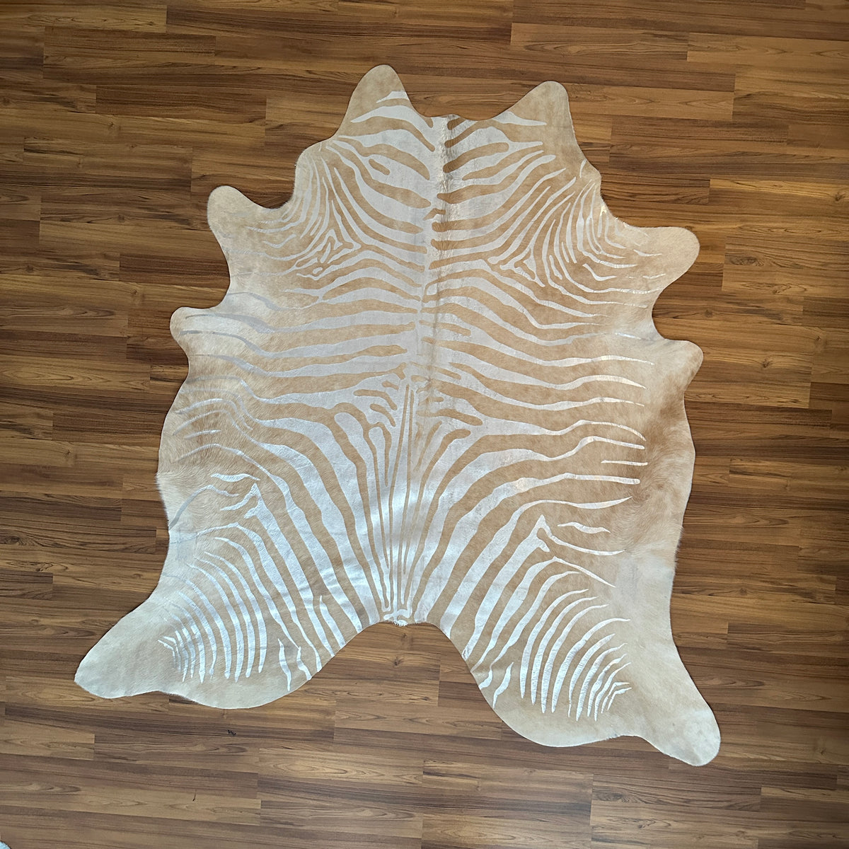 Brown and White zebra print cowhide rug, full overhead view — Bold zebra-stripe pattern radiating from center in cream and wa