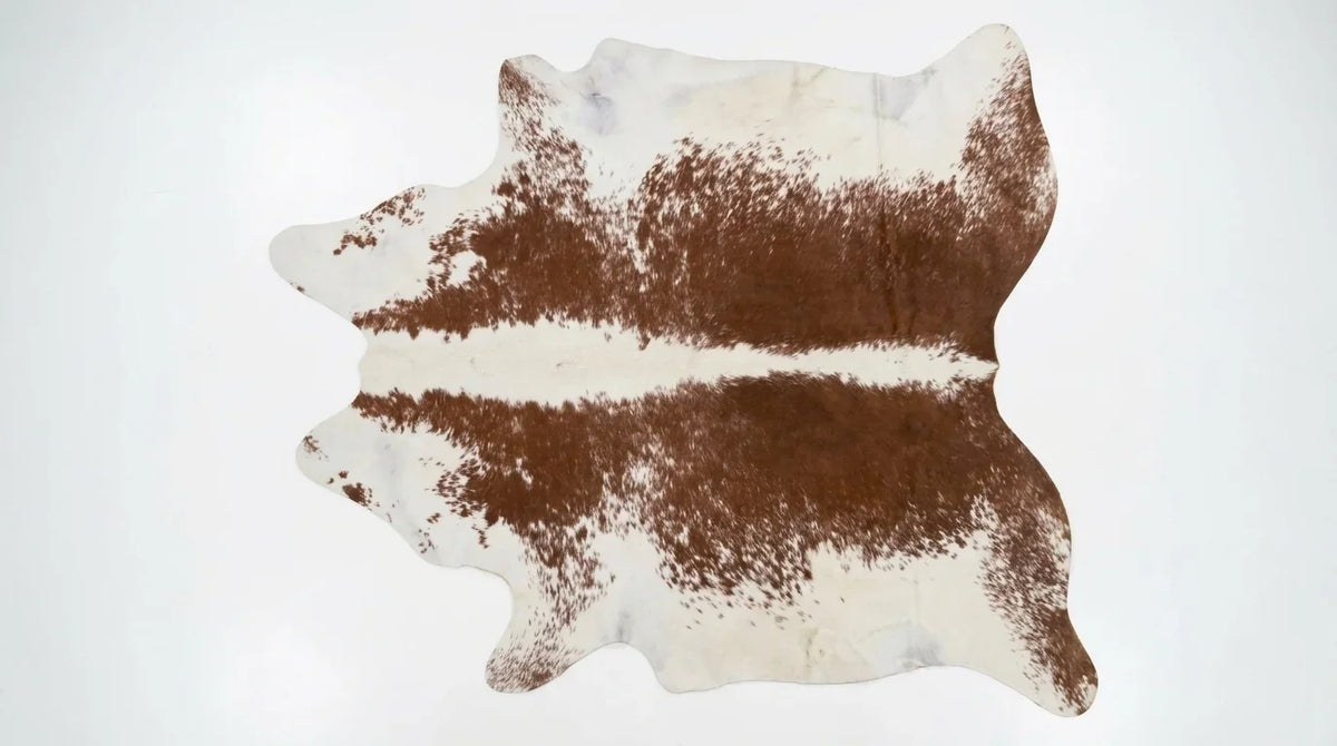 Brown and White cowhide rug flat lay on white background showing full hide shape