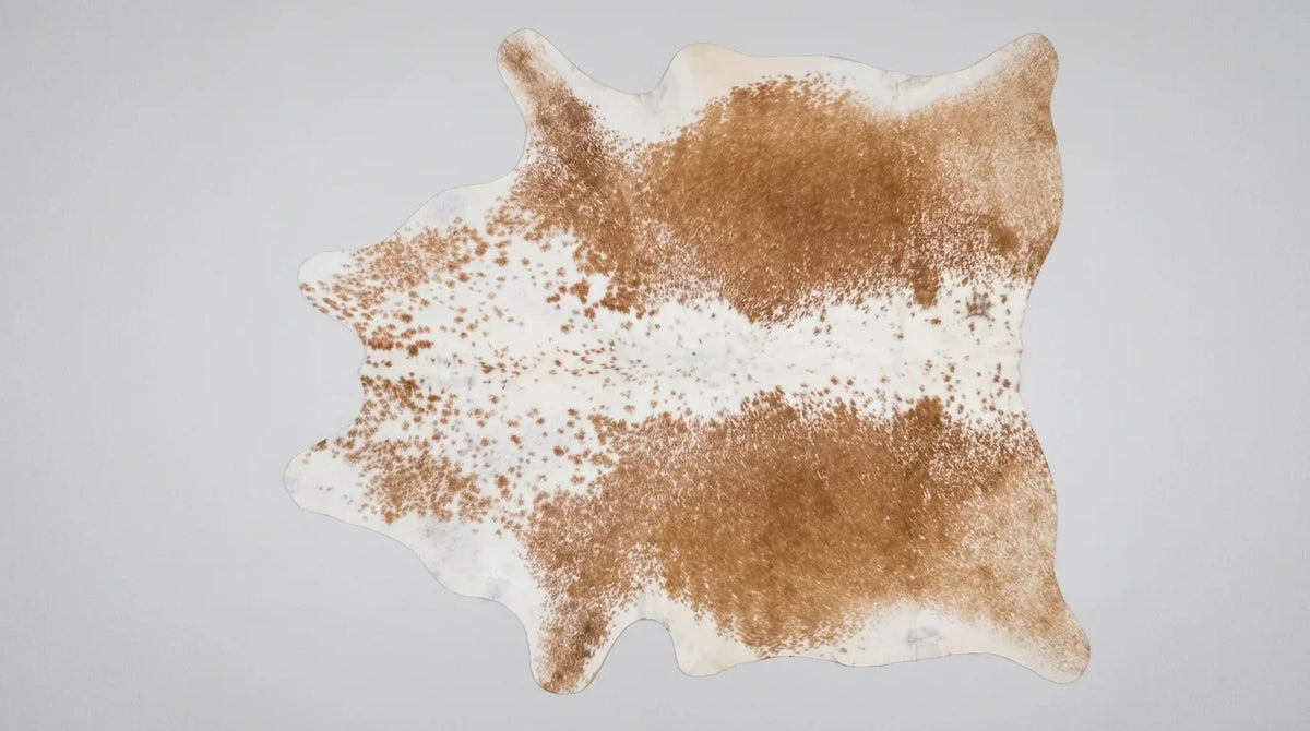 Brown and White cowhide rug flat lay on white background showing full hide shape
