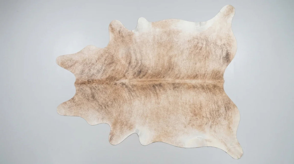 Brown and White cowhide rug flat lay on white background showing full hide shape