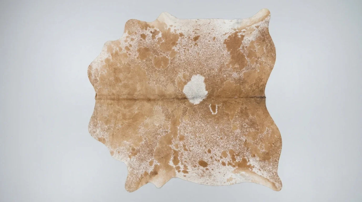 Brown and White cowhide rug flat lay on white background showing full hide shape