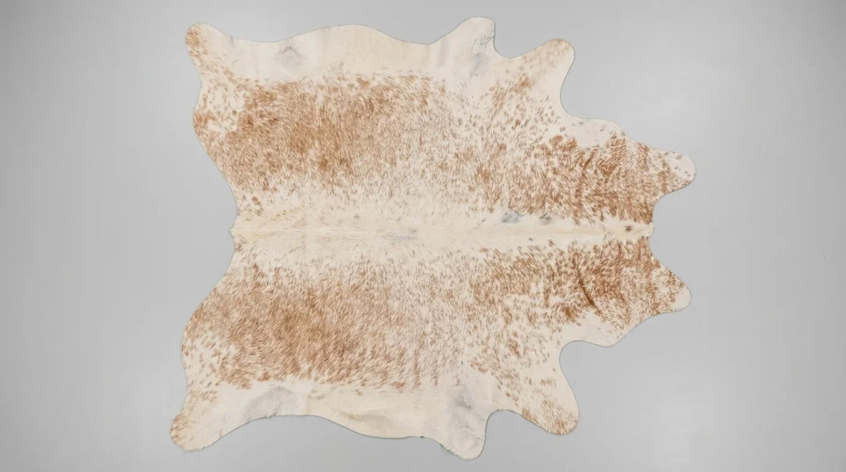 Brown and White cowhide rug flat lay on white background showing full hide shape