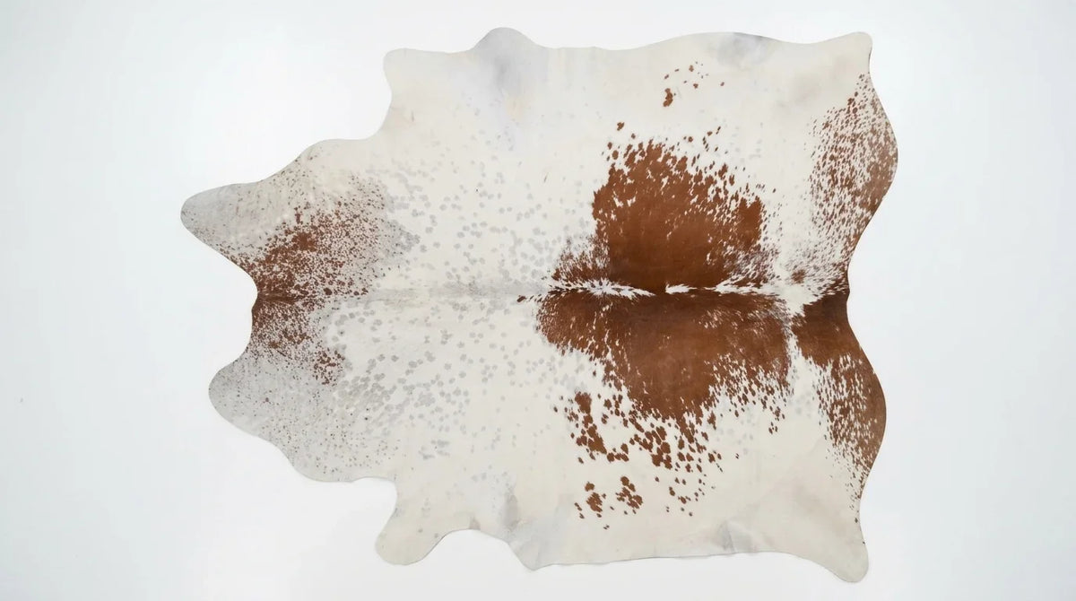 Brown and White cowhide rug flat lay on white background showing full hide shape
