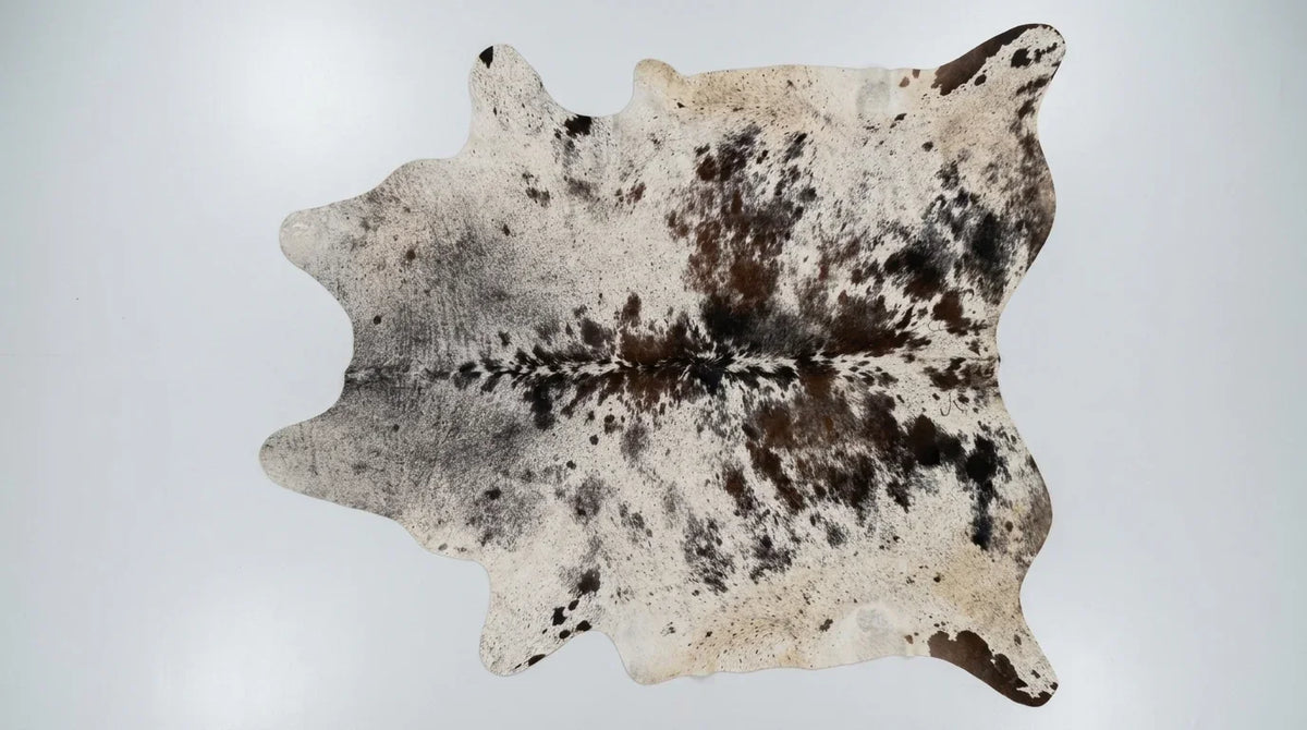 Brown and White cowhide rug flat lay on white background showing full hide shape