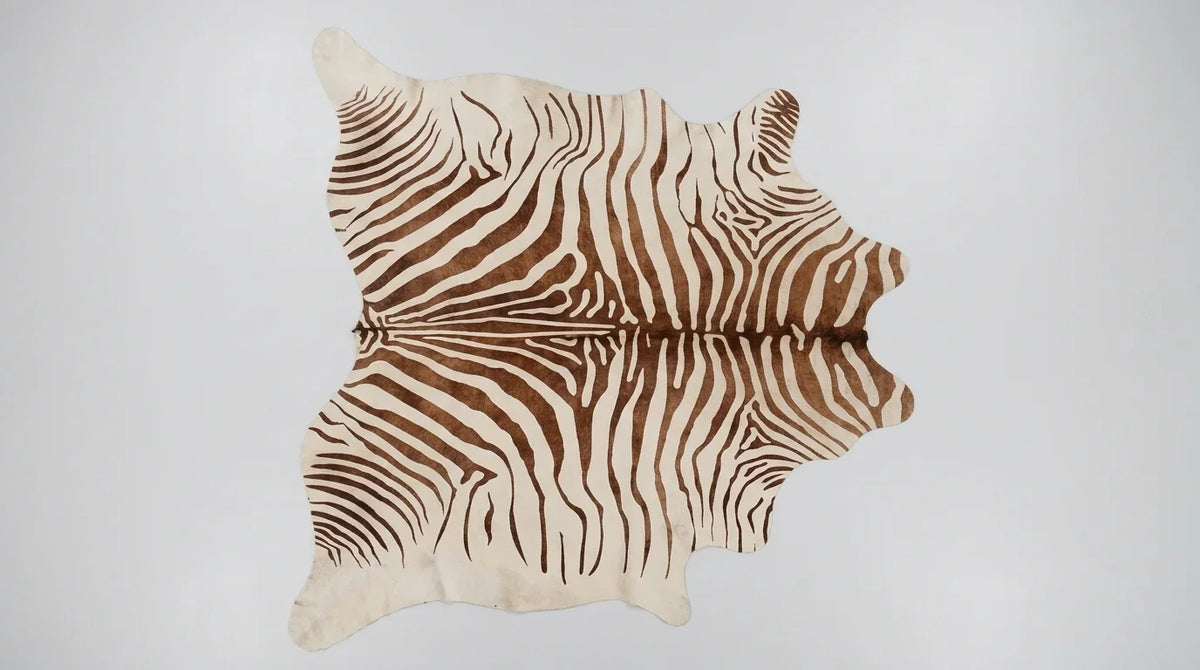 Brown and White cowhide rug flat lay on white background showing full hide shape