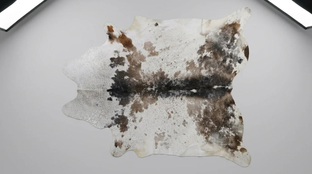 Brown and White cowhide rug flat lay on white background showing full hide shape