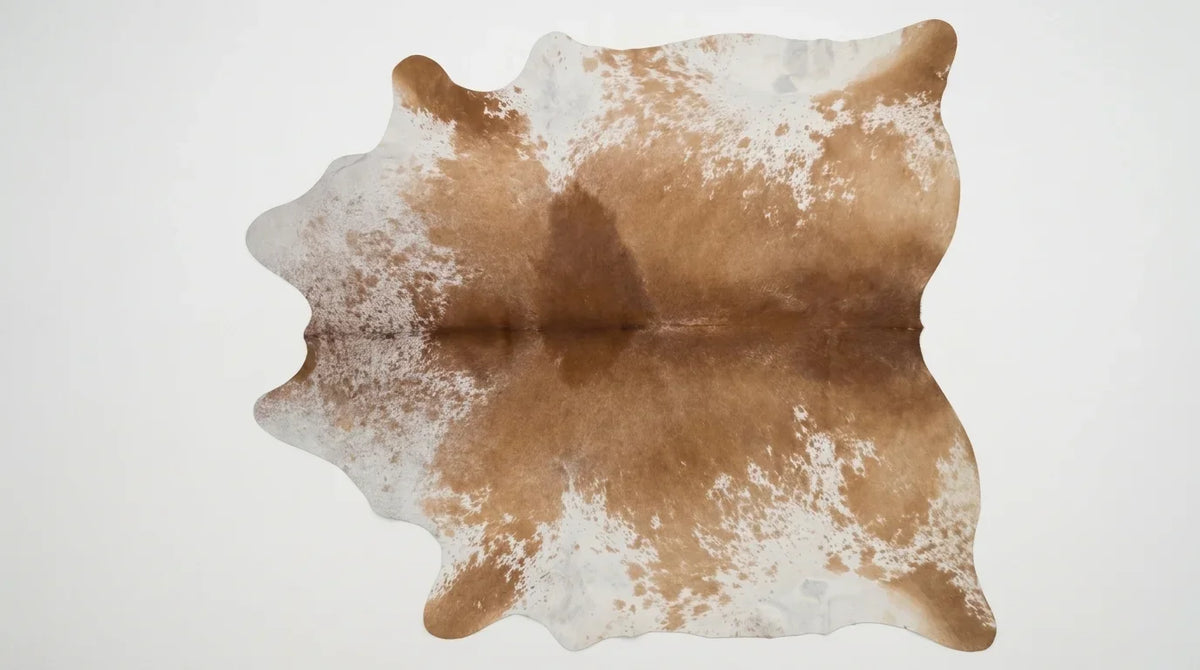 Brown and White cowhide rug flat lay on white background showing full hide shape