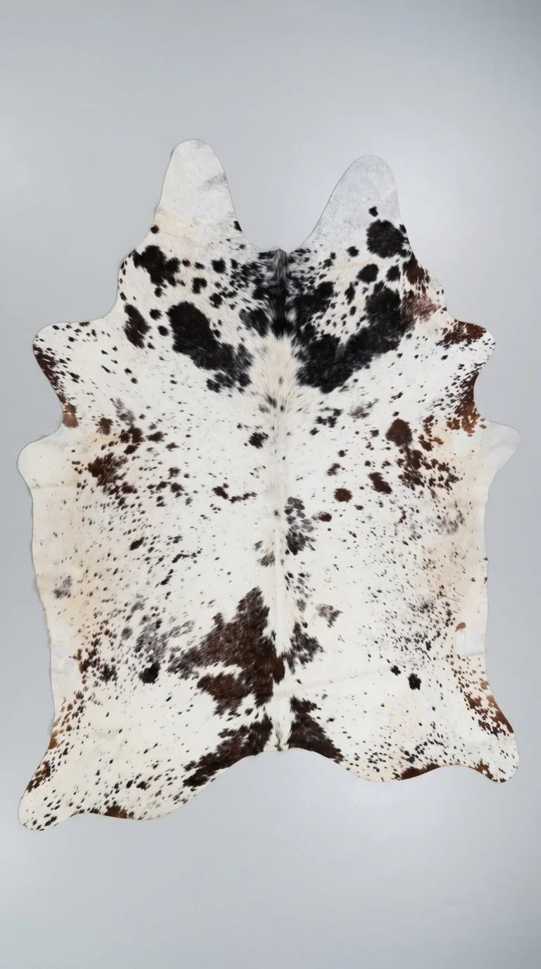 Brown and White cowhide rug flat lay on white background showing full hide shape