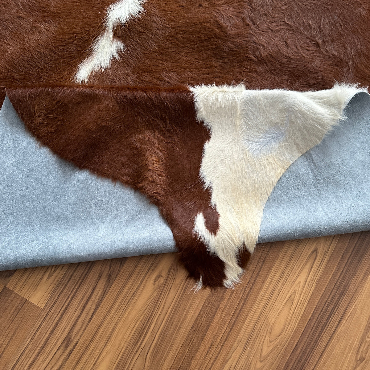 Close-up texture of Brown and White cowhide rug — Large irregular chocolate-brown patches with cream and white accents across