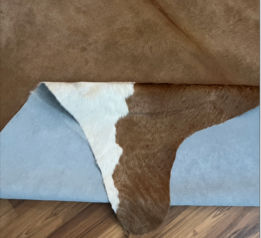 Close-up texture of Brown and White cowhide rug — Large irregular taupe-brown patches over white base with natural hide marki