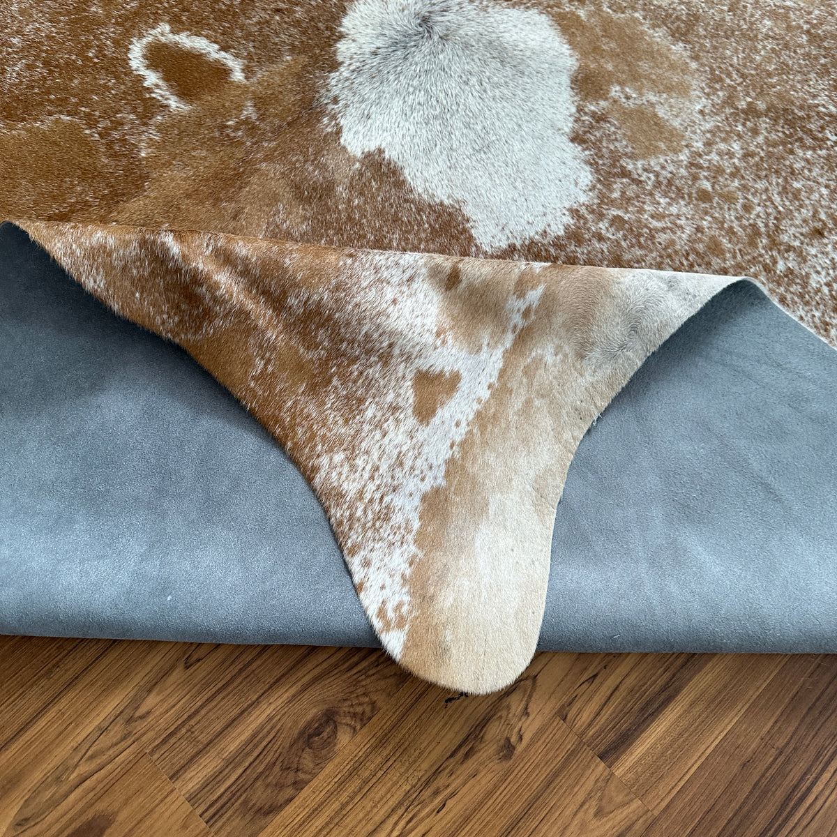 Close-up texture of Brown and White cowhide rug — Large irregular tan and chocolate brown patches over cream and white base