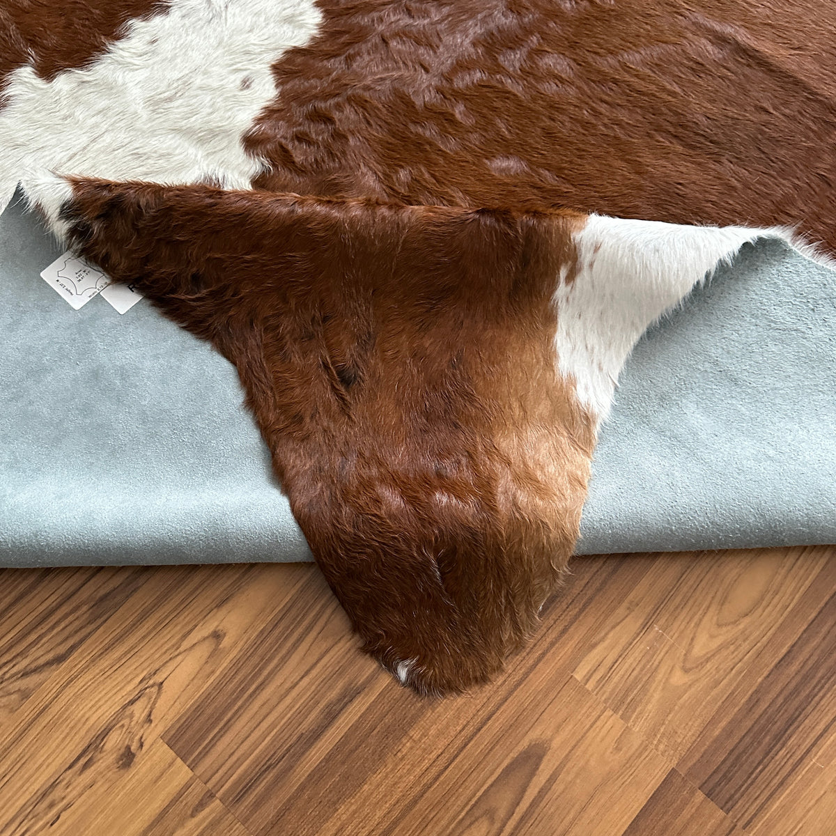Close-up texture of Brown and White cowhide rug — Large irregular chocolate brown patches with cream and white accents over n