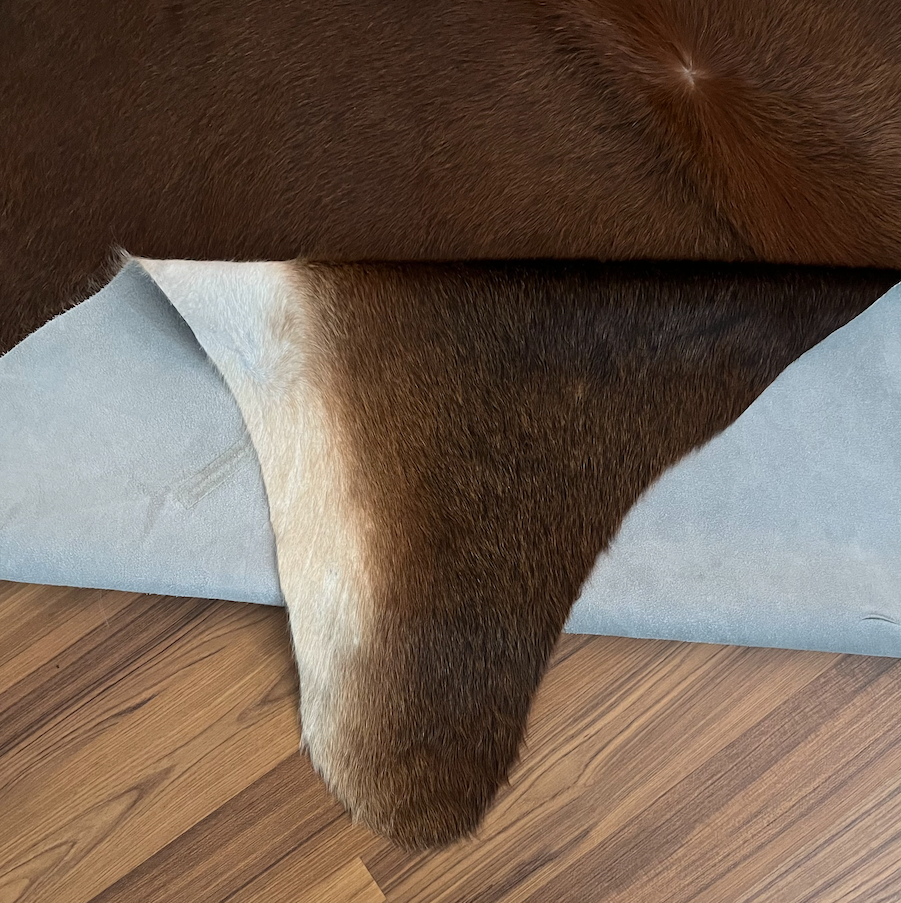 Close-up texture of Brown and White cowhide rug — Large irregular dark brown patches over cream and white base with natural h
