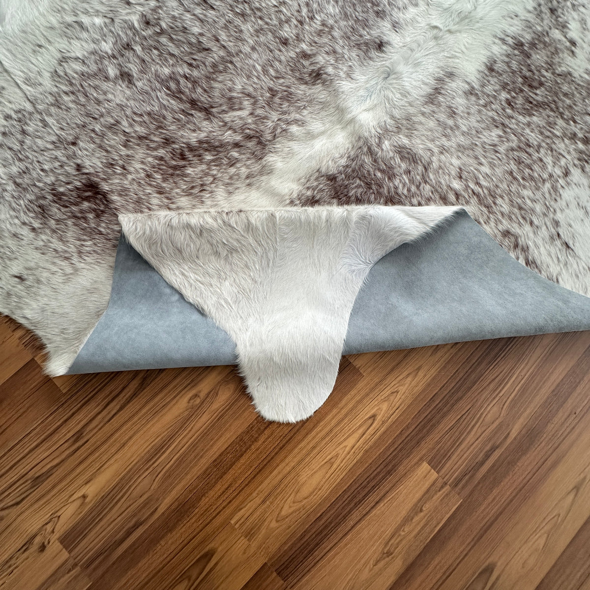 Close-up texture of Brown and White cowhide rug — Large irregular brown patches and speckles over cream and white base