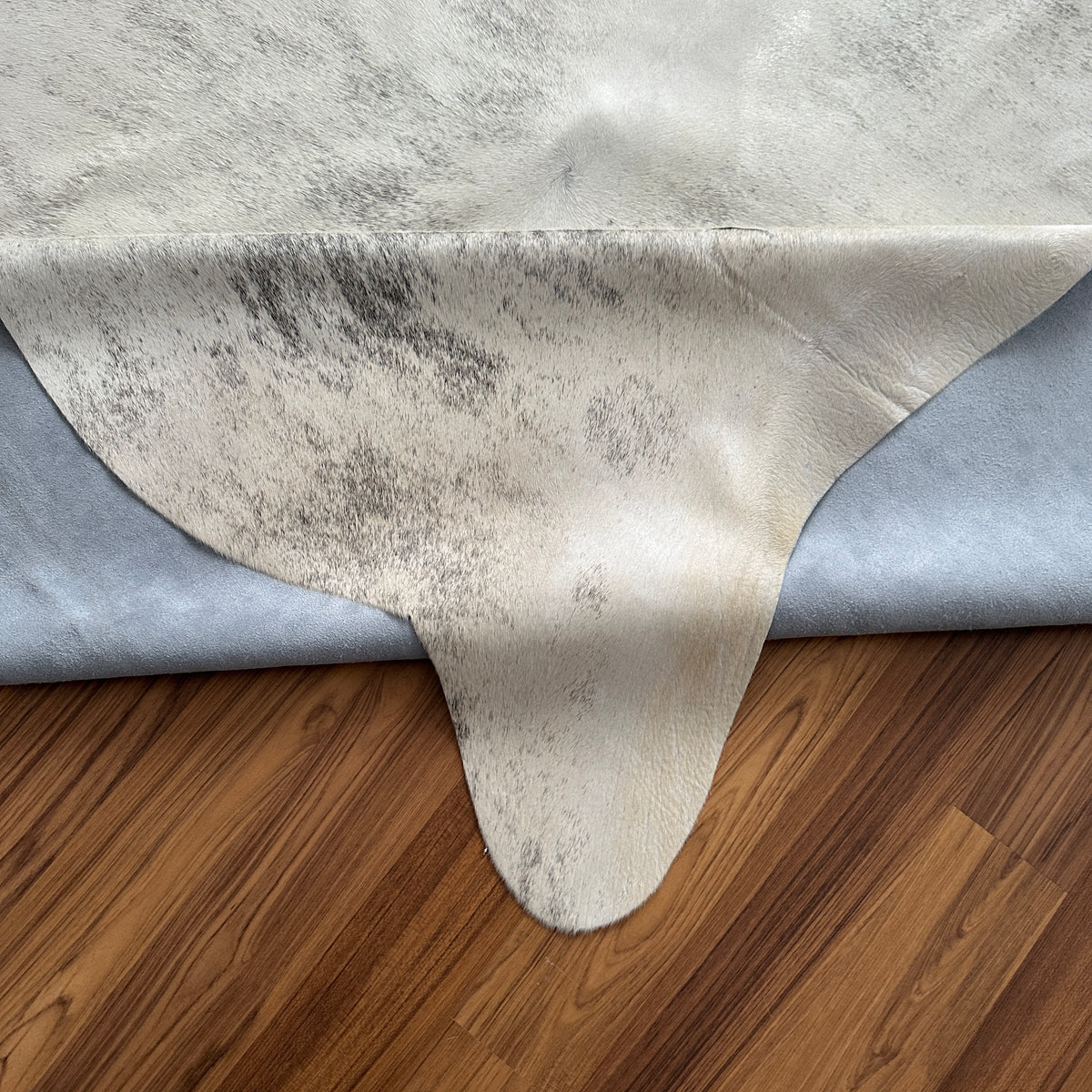 Close-up texture of Brown and White cowhide rug — Large irregular dark brown and gray patches over cream and ivory base