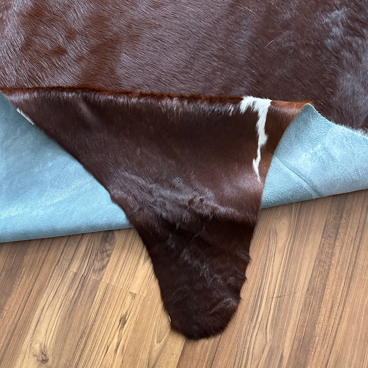 Close-up texture of Brown and White cowhide rug — Large irregular dark brown patches with white markings over cream base