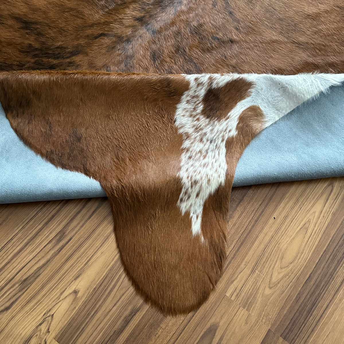 Close-up texture of Brown and White cowhide rug — Large irregular chocolate brown patches with white markings on cream base