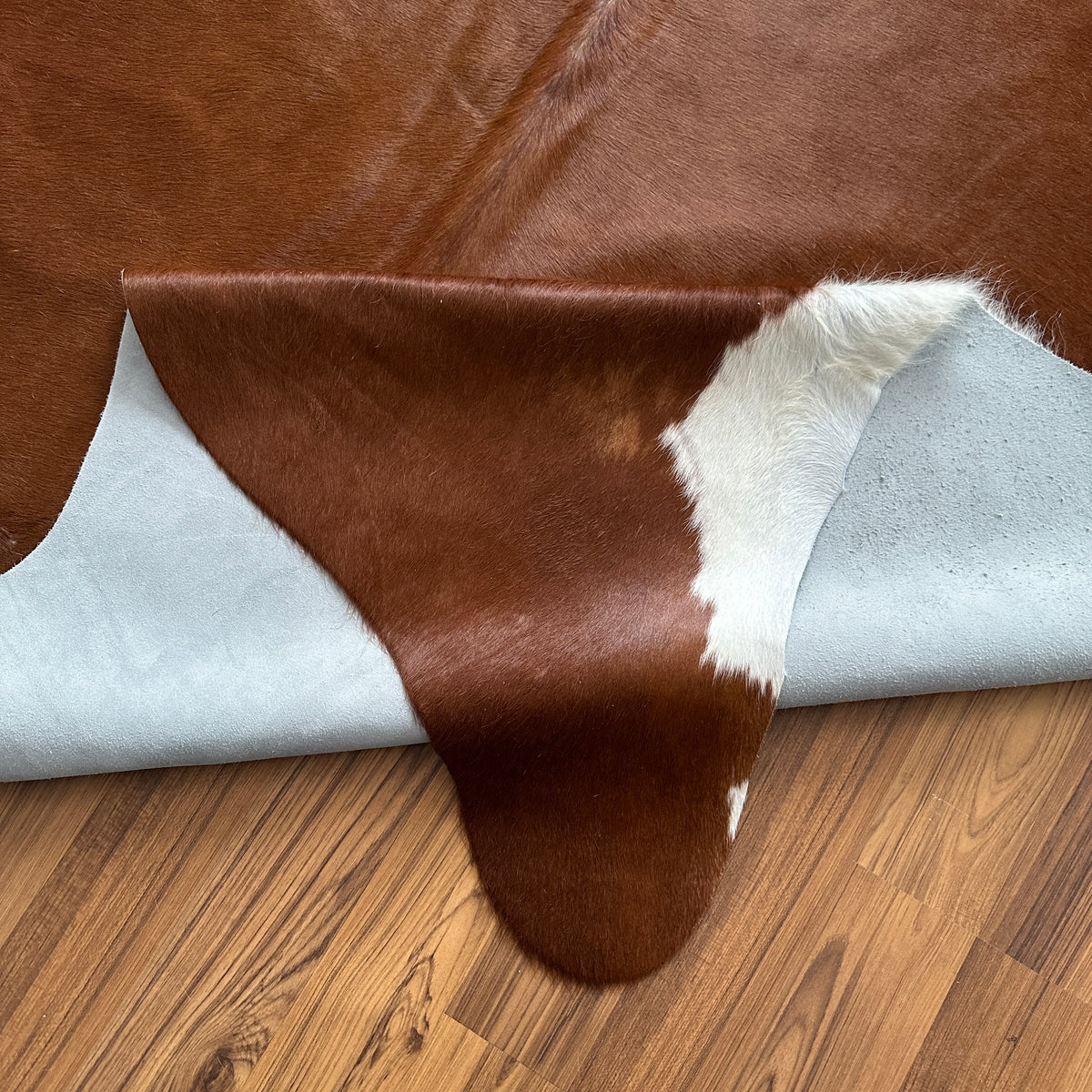 Close-up texture of Brown and White cowhide rug — Large irregular chocolate brown patches over cream and white base
