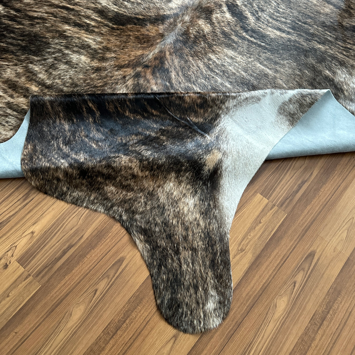 Close-up texture of Brown and White cowhide rug — Large irregular dark brown patches with white markings over grey-brown base
