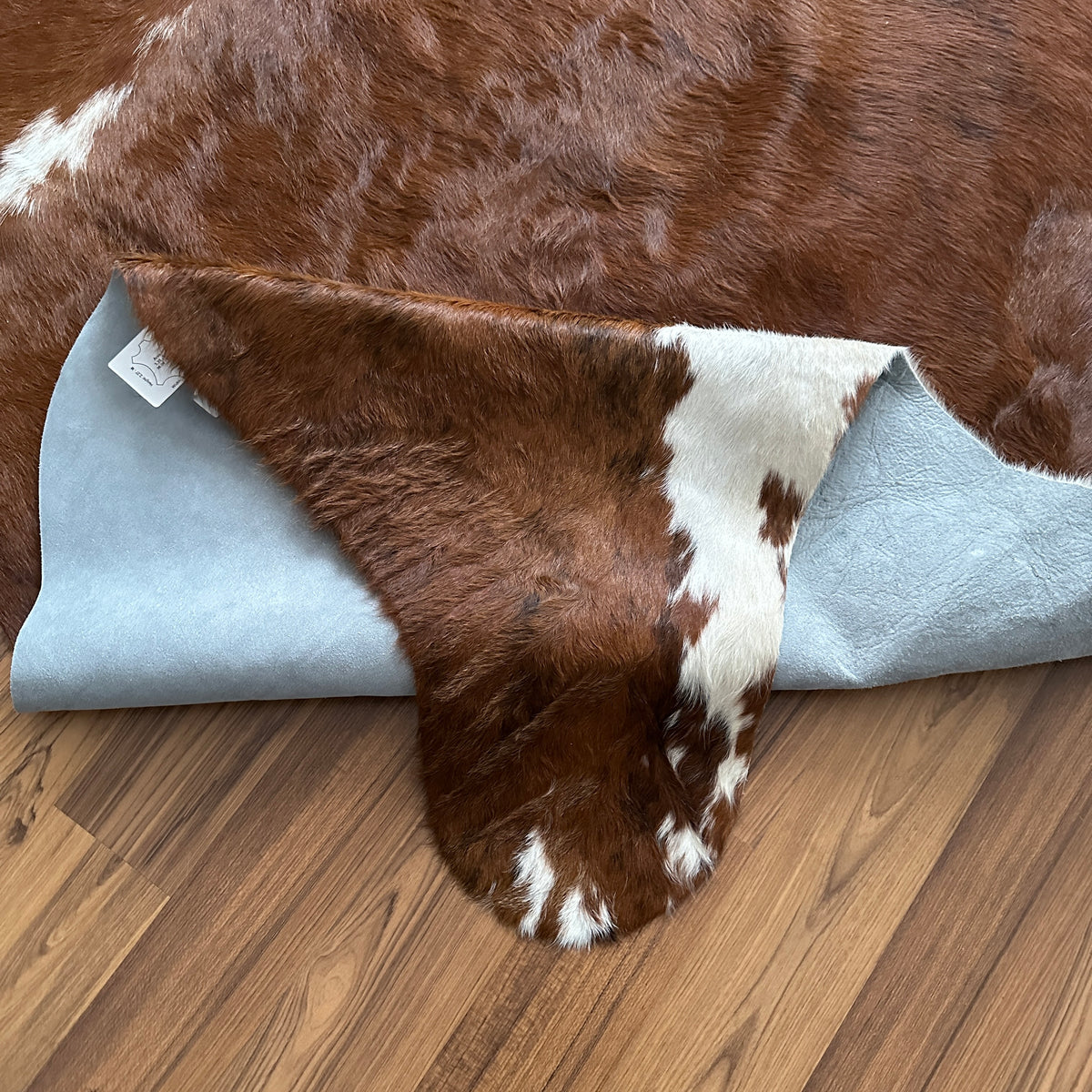 Close-up texture of Brown and White cowhide rug — Large irregular chocolate brown patches with cream and white markings over 