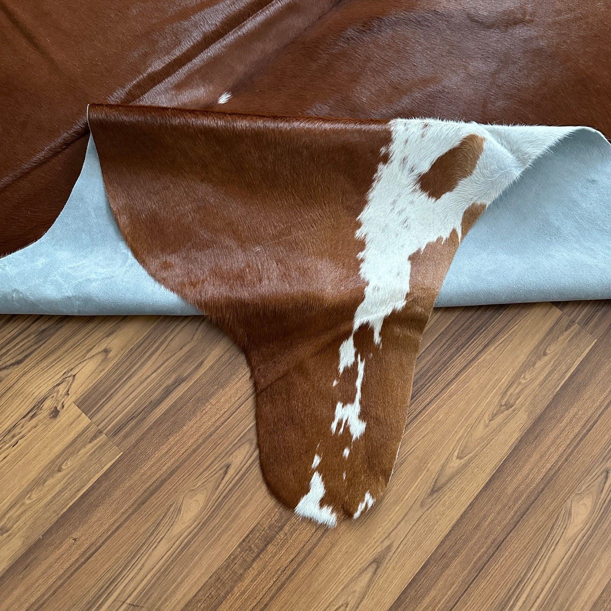 Close-up texture of Brown and White cowhide rug — Large irregular chocolate brown patches with white markings across natural 