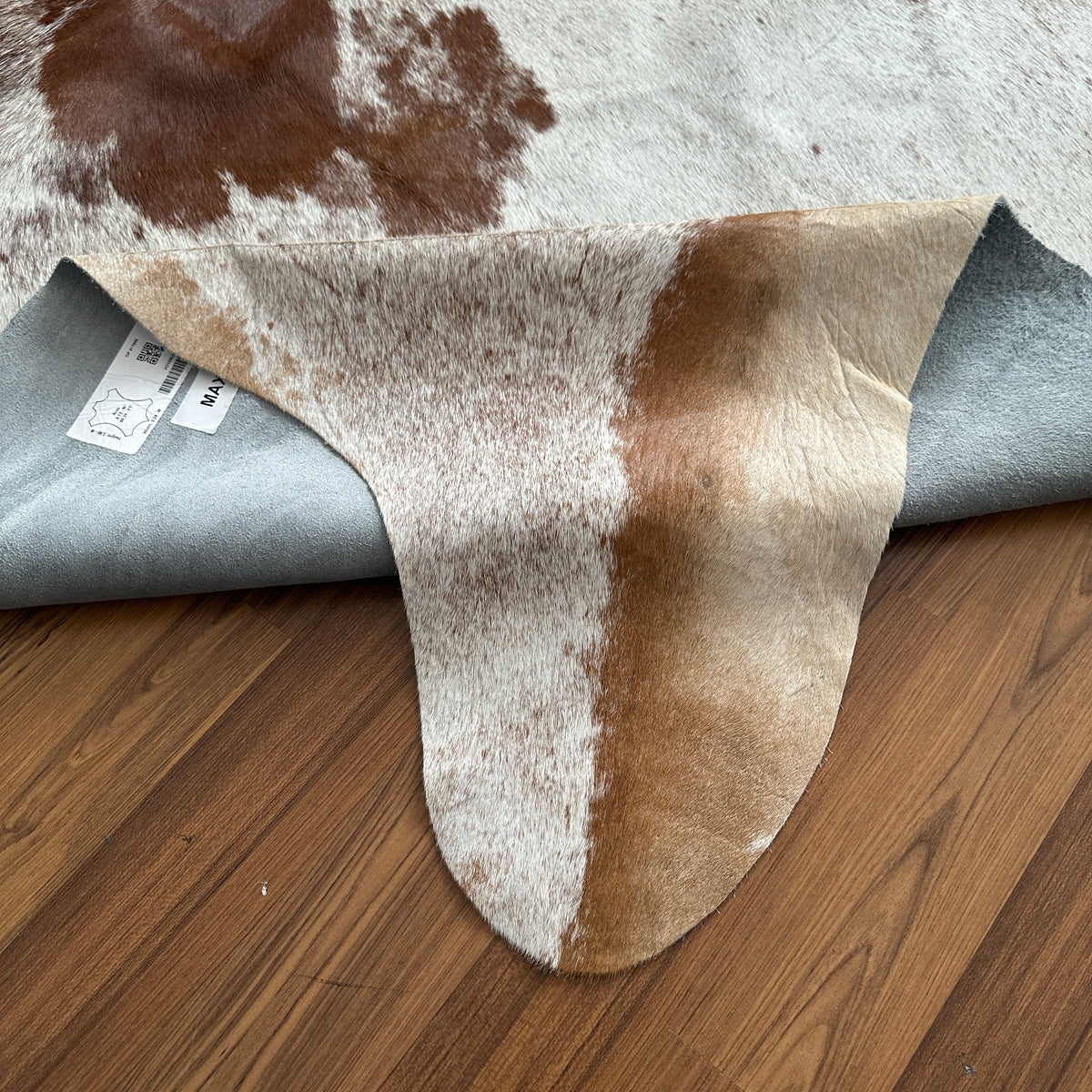 Close-up texture of Brown and White cowhide rug — Large and medium irregular chocolate brown patches scattered across cream b