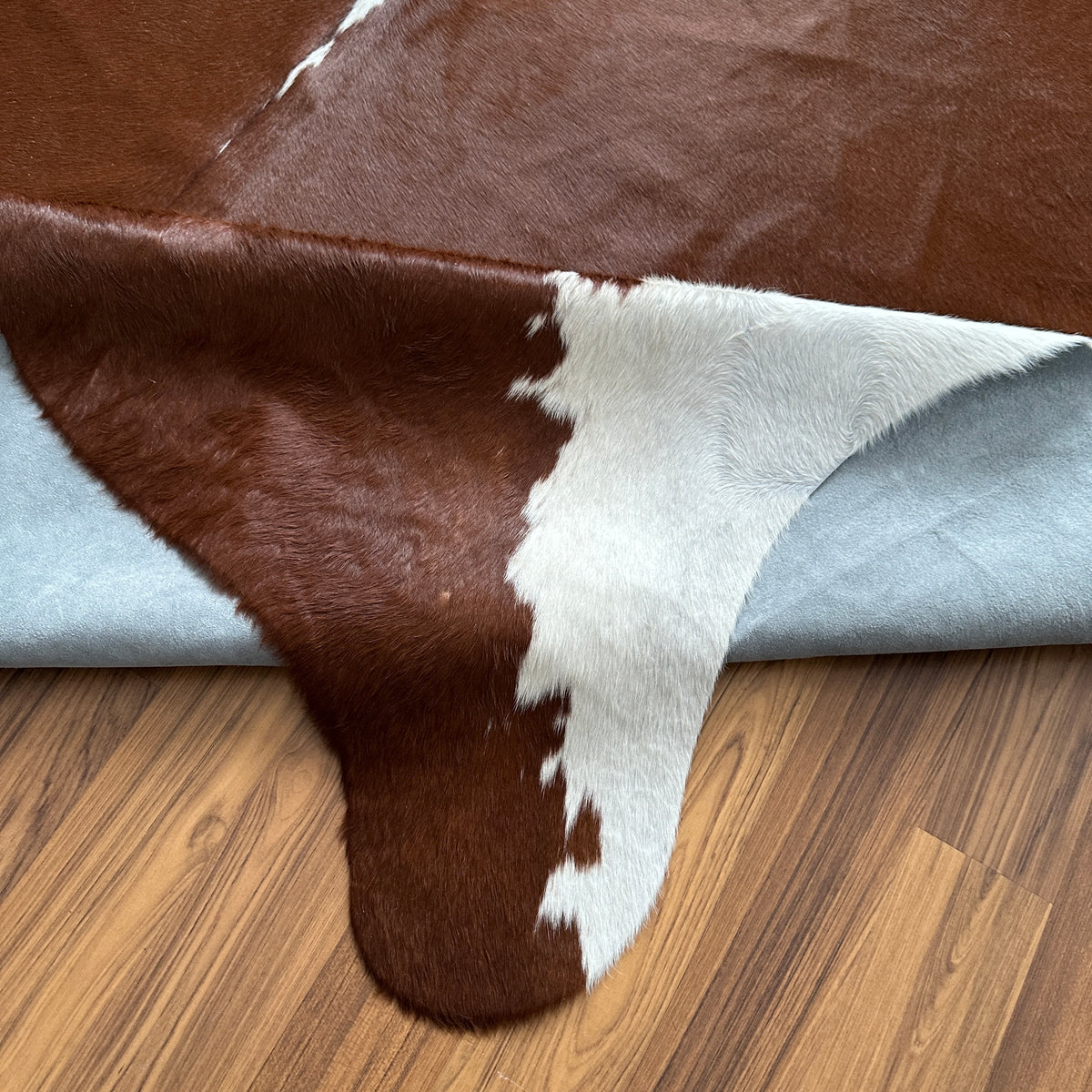 Close-up texture of Brown and White cowhide rug — Large irregular dark brown patches with white markings across natural hide