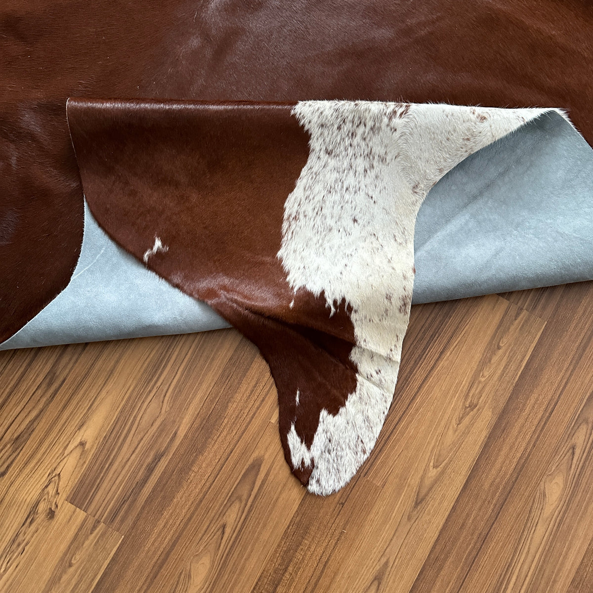 Close-up texture of Brown and White cowhide rug — Large irregular dark chocolate-brown patches with fine salt-and-pepper spec