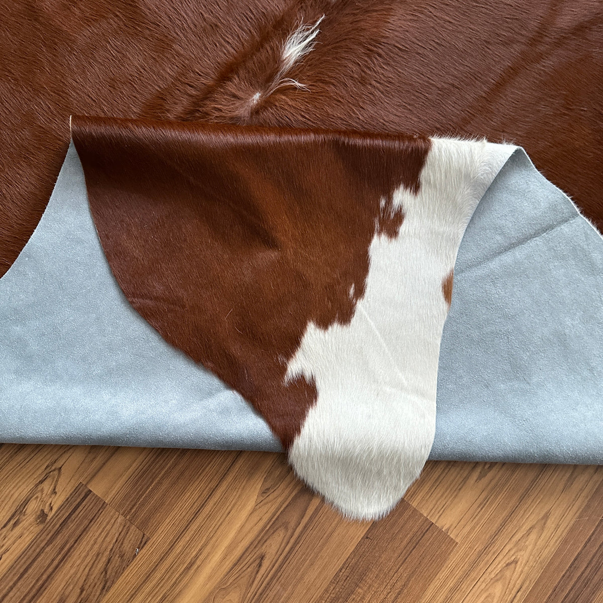 Close-up texture of Brown and White cowhide rug — Large irregular dark brown patches with white markings and cream base