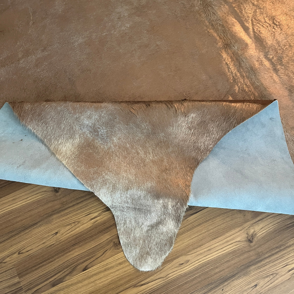 Close-up texture of Brown and White cowhide rug — Large irregular dark brown patches over light tan and cream base