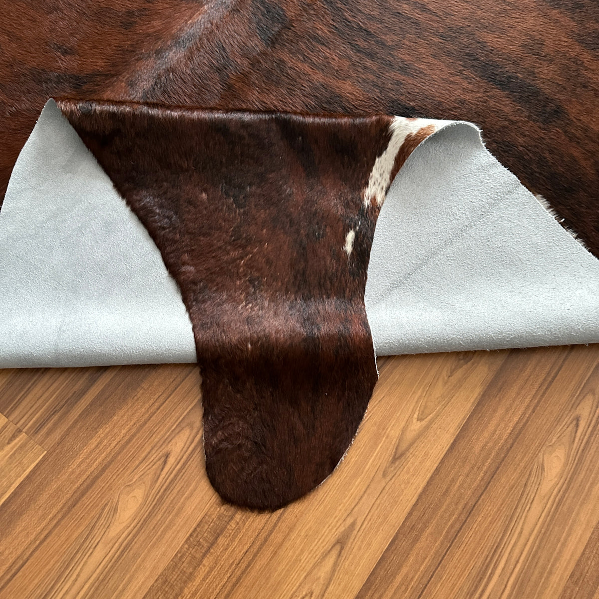 Close-up texture of Brown and White cowhide rug — Large irregular dark brown patches with white spots and markings over a bro
