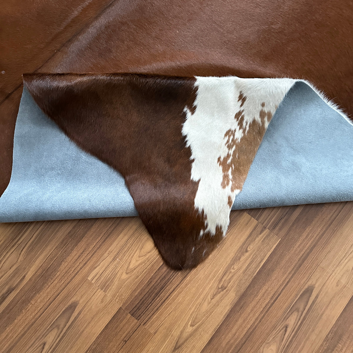 Close-up texture of Brown and White cowhide rug — Large irregular chocolate brown patches with white markings over deep brown