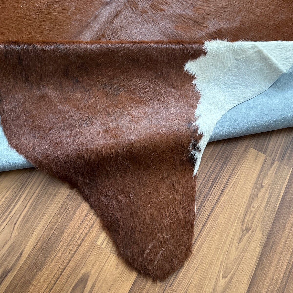 Close-up texture of Brown and White cowhide rug — Large irregular chocolate brown patches with white markings across natural 