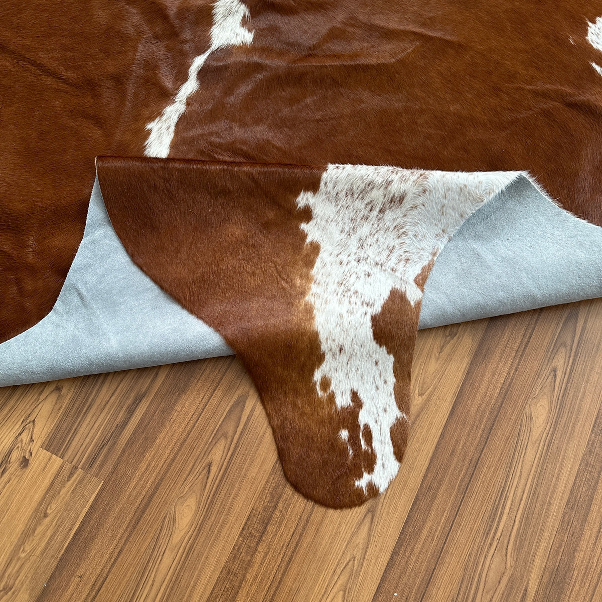 Close-up texture of Brown and White cowhide rug — Large irregular chocolate brown patches with white speckled accents over a 