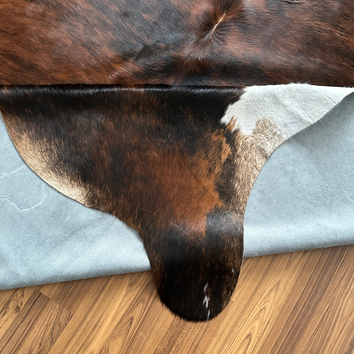 Close-up texture of Brown and White cowhide rug — Large irregular dark brown patches with white accents over a medium brown b