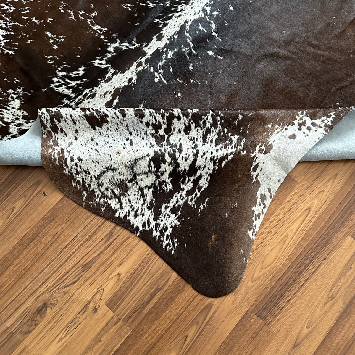 Close-up texture of Brown and White cowhide rug — Large irregular chocolate brown patches with cream and white accents over d