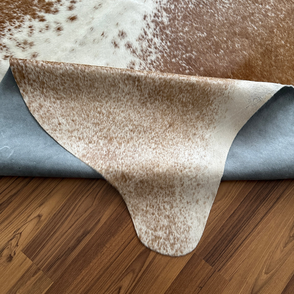 Close-up texture of Brown and White cowhide rug — Large irregular tan and brown patches over cream and white base