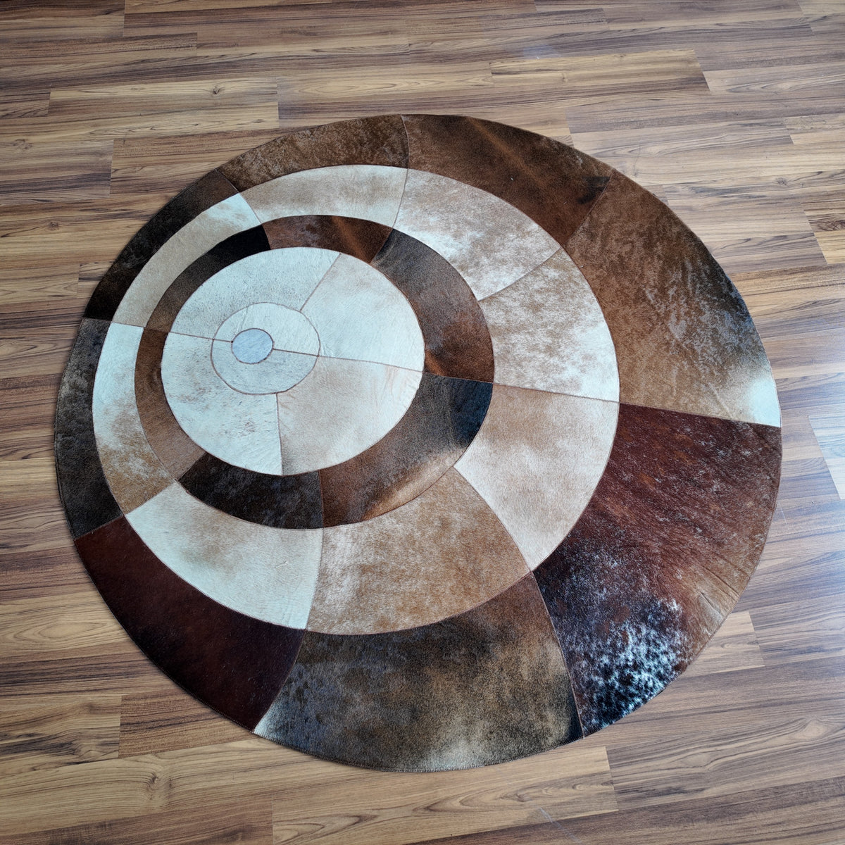 Brown and White round patchwork cowhide rug, full overhead view — Concentric circular bands in cream, light brown, medium bro