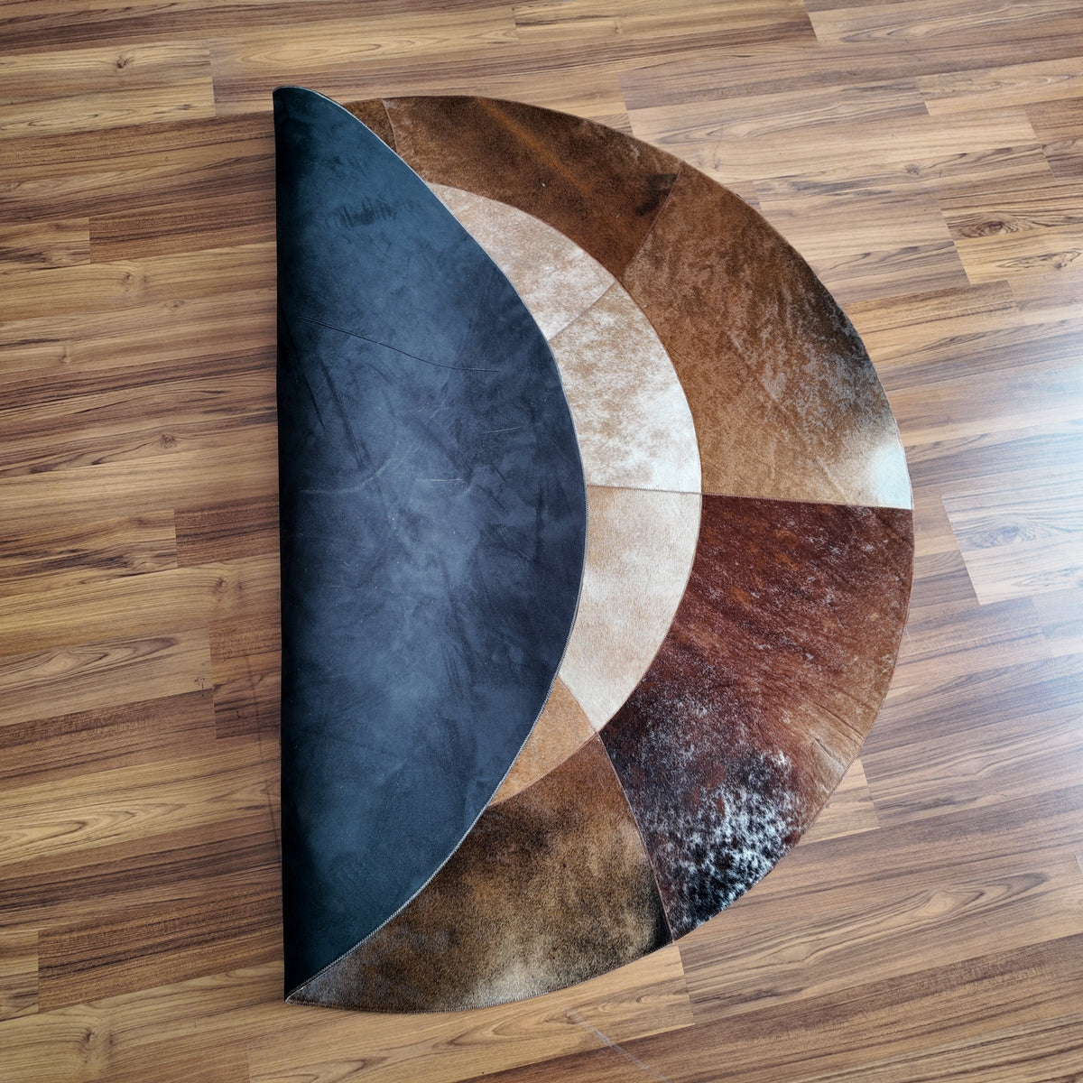 Close-up texture of Brown and White round patchwork cowhide rug — Concentric circular bands in cream, light brown, medium bro