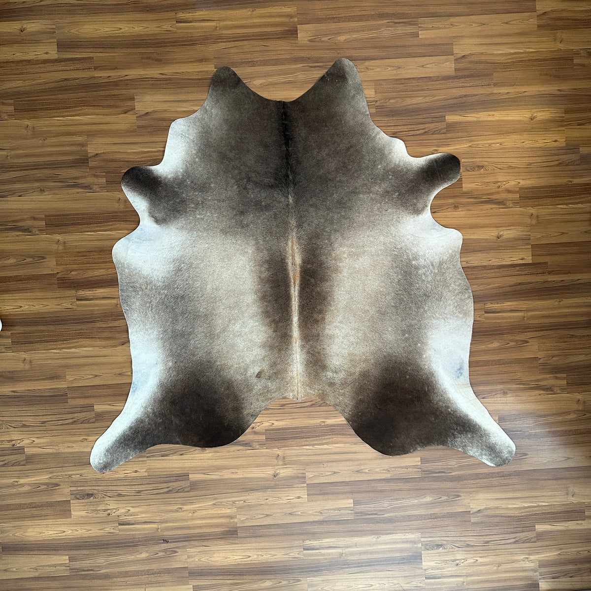 Grey cowhide rug, full overhead view — Large irregular dark grey and charcoal patches over light grey base