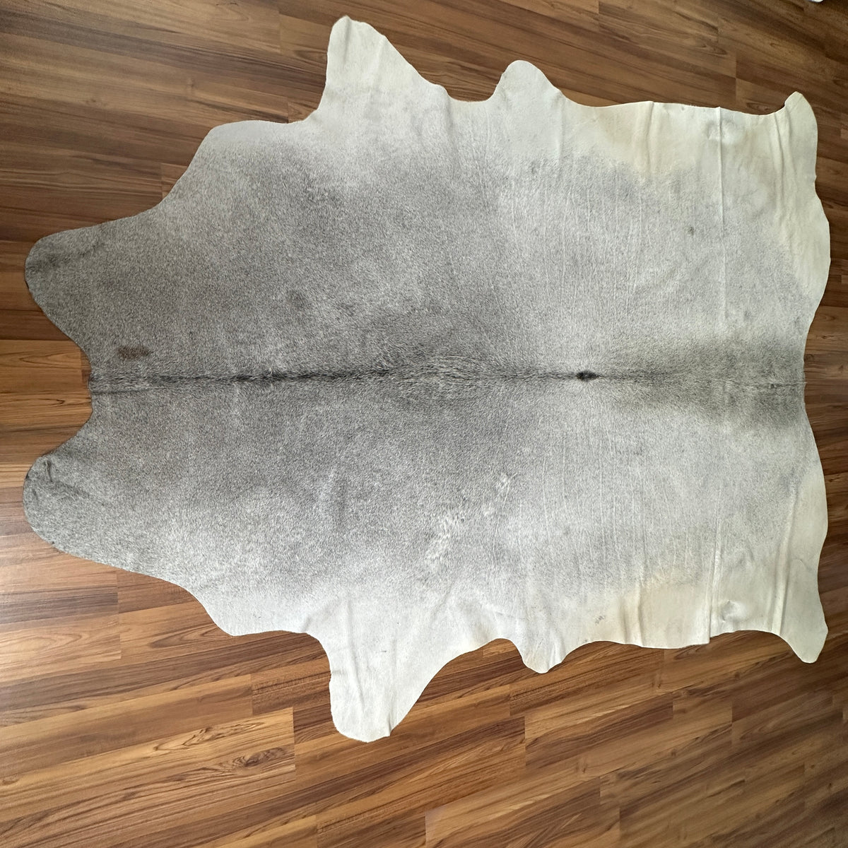 Grey cowhide rug, full overhead view — Large irregular patches of light grey and cream over a neutral base