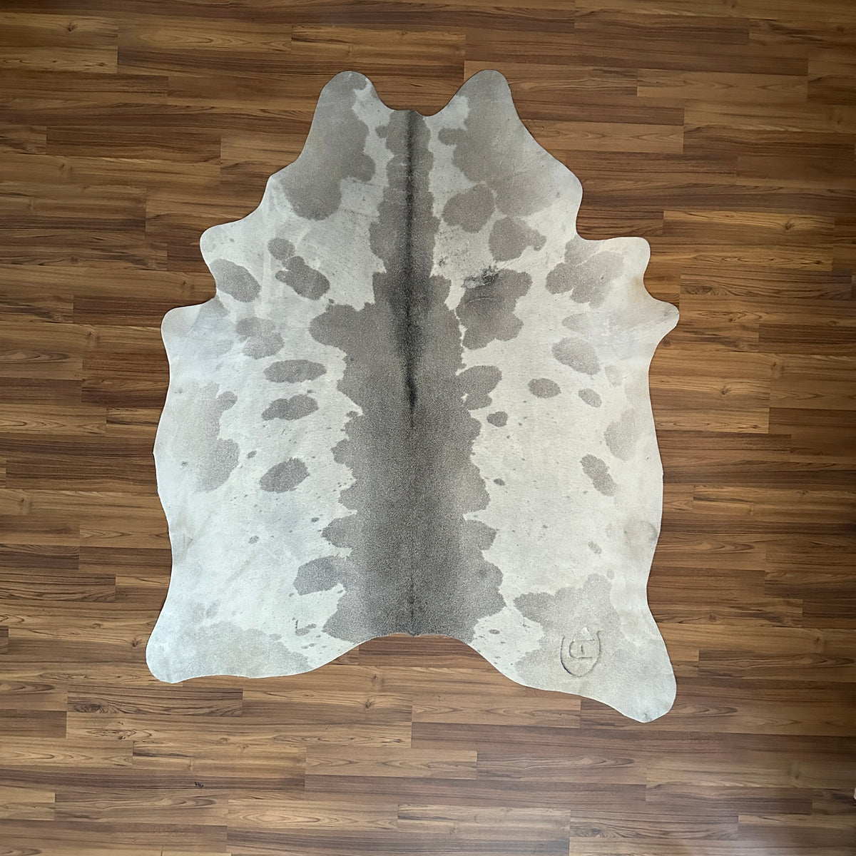 Grey cowhide rug, full overhead view — Large irregular grey patches over cream and white base with darker spine stripe